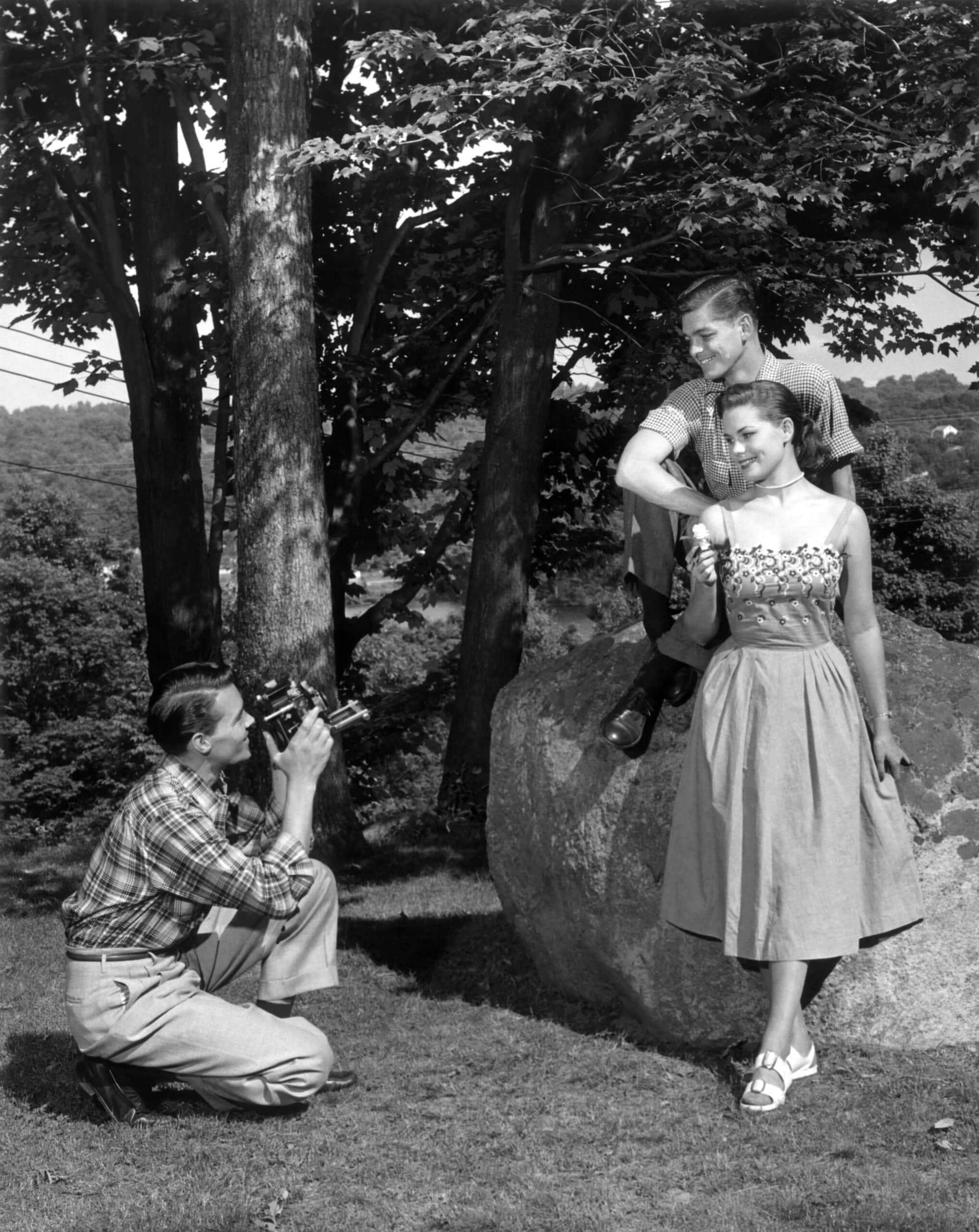 Family taking photos outdoors with trees and rocks in the background.