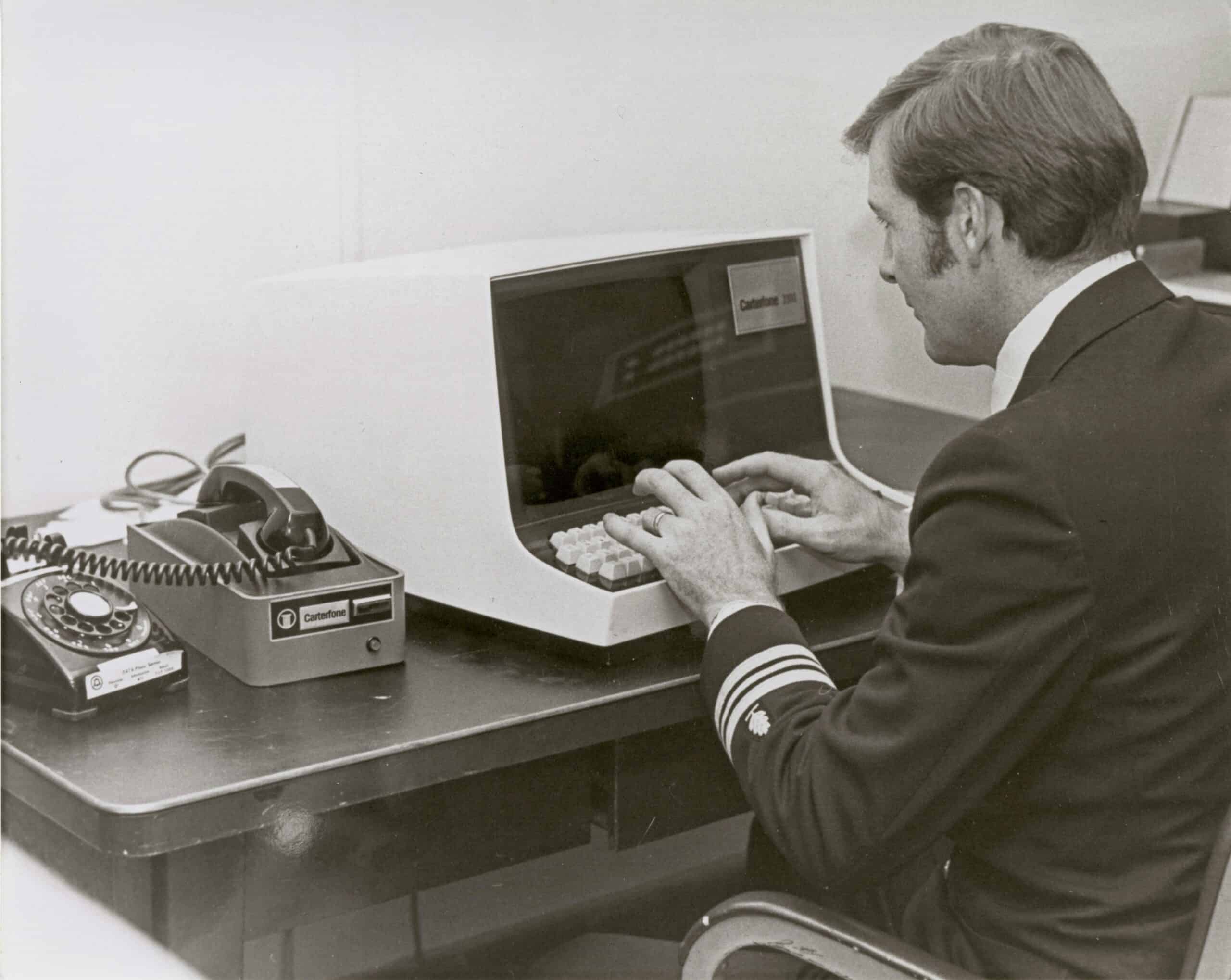 Man in uniform using vintage computer in an office setting.